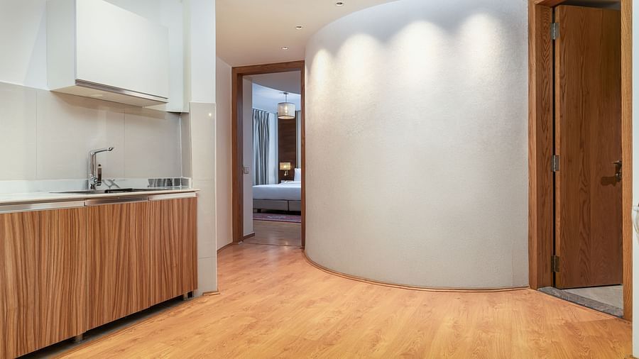 A compact kitchenette area with elegant white and wood tones - Sarovar Premiere, Srinagar